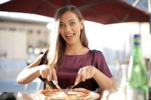 Woman-in-Purple-Top-While-Slicing-Pizza